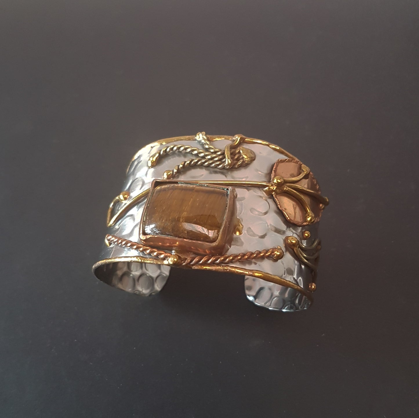 Silver cuff bracelet with rectangle shape tigereye stone. Adjustable fit. Mixed metal artisan design with copper & brass detail.