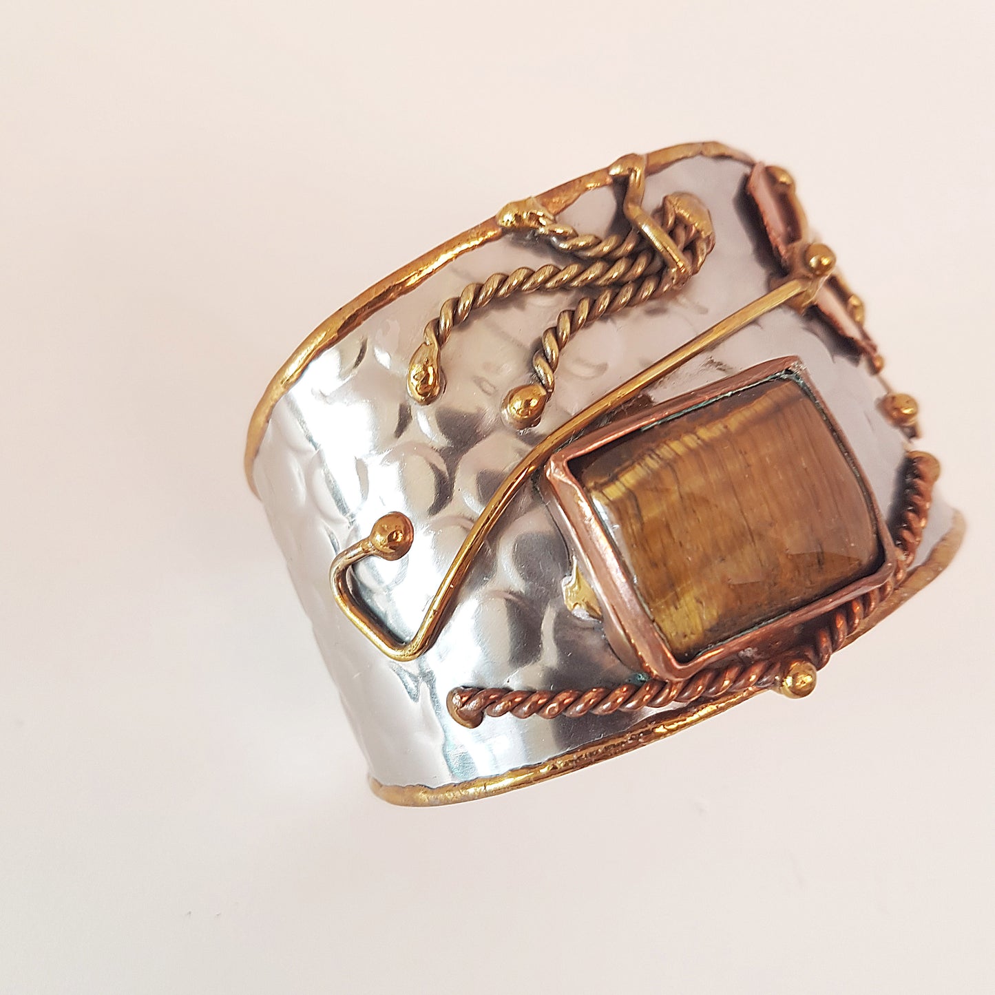 Silver cuff bracelet with rectangle shape tigereye stone. Adjustable fit. Mixed metal artisan design with copper & brass detail.