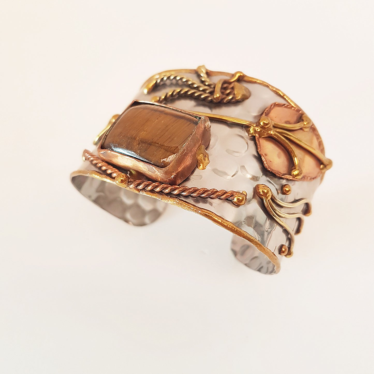 Silver cuff bracelet with rectangle shape tigereye stone. Adjustable fit. Mixed metal artisan design with copper & brass detail.
