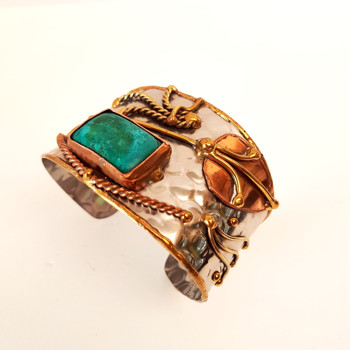 Silver cuff bracelet with an inlaid turquoise stone. Hammered trimetal design with copper & brass detail.