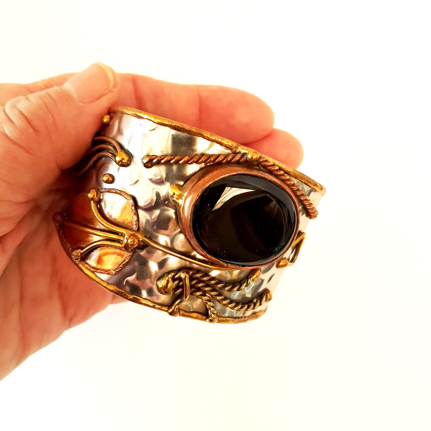Silver cuff bracelet with a large oval shaped black onyx stone. Unique mixed metal design with copper, brass and silver. Flexible adjustable size.