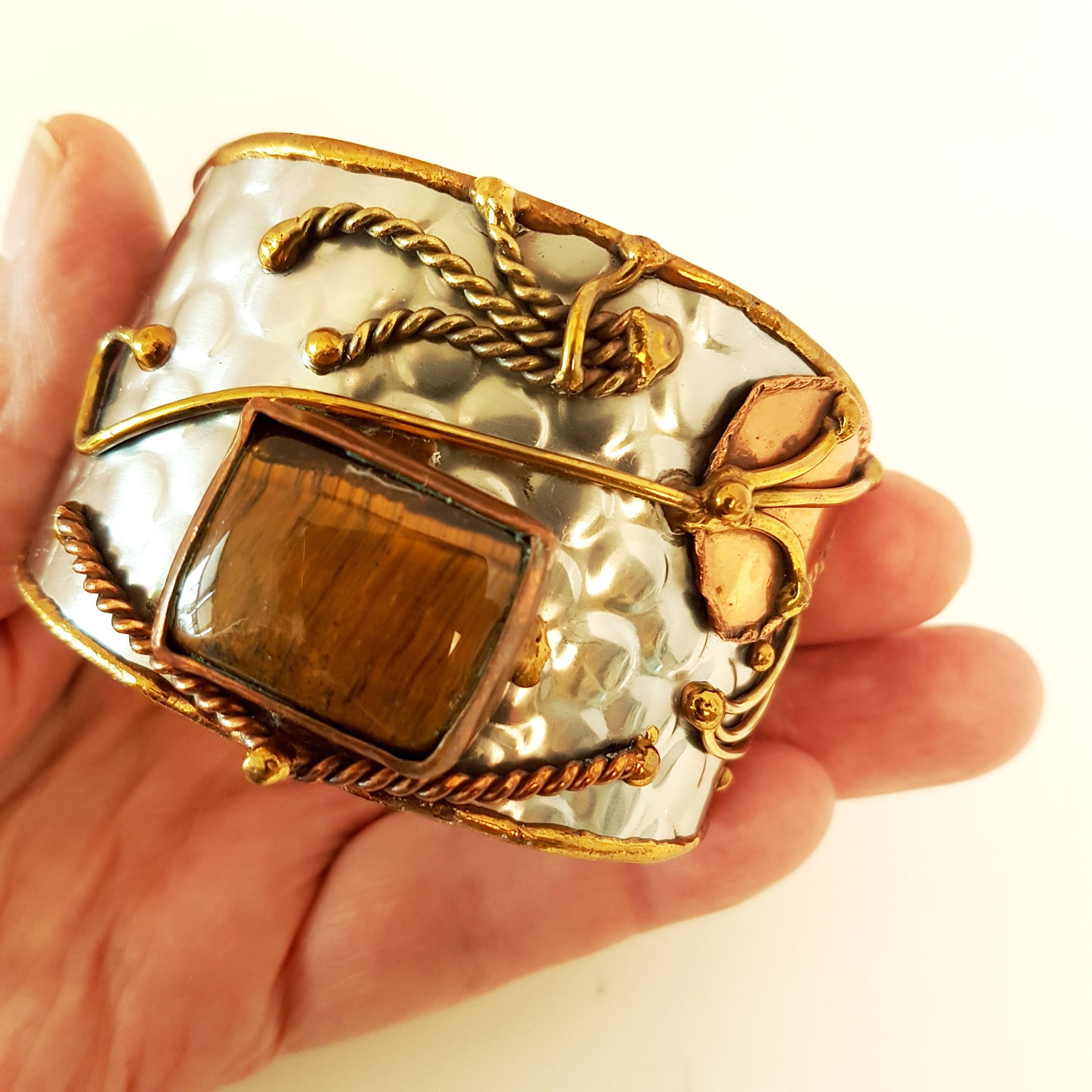 Silver cuff bracelet with rectangle shape tigereye stone. Adjustable fit. Mixed metal artisan design with copper & brass detail.