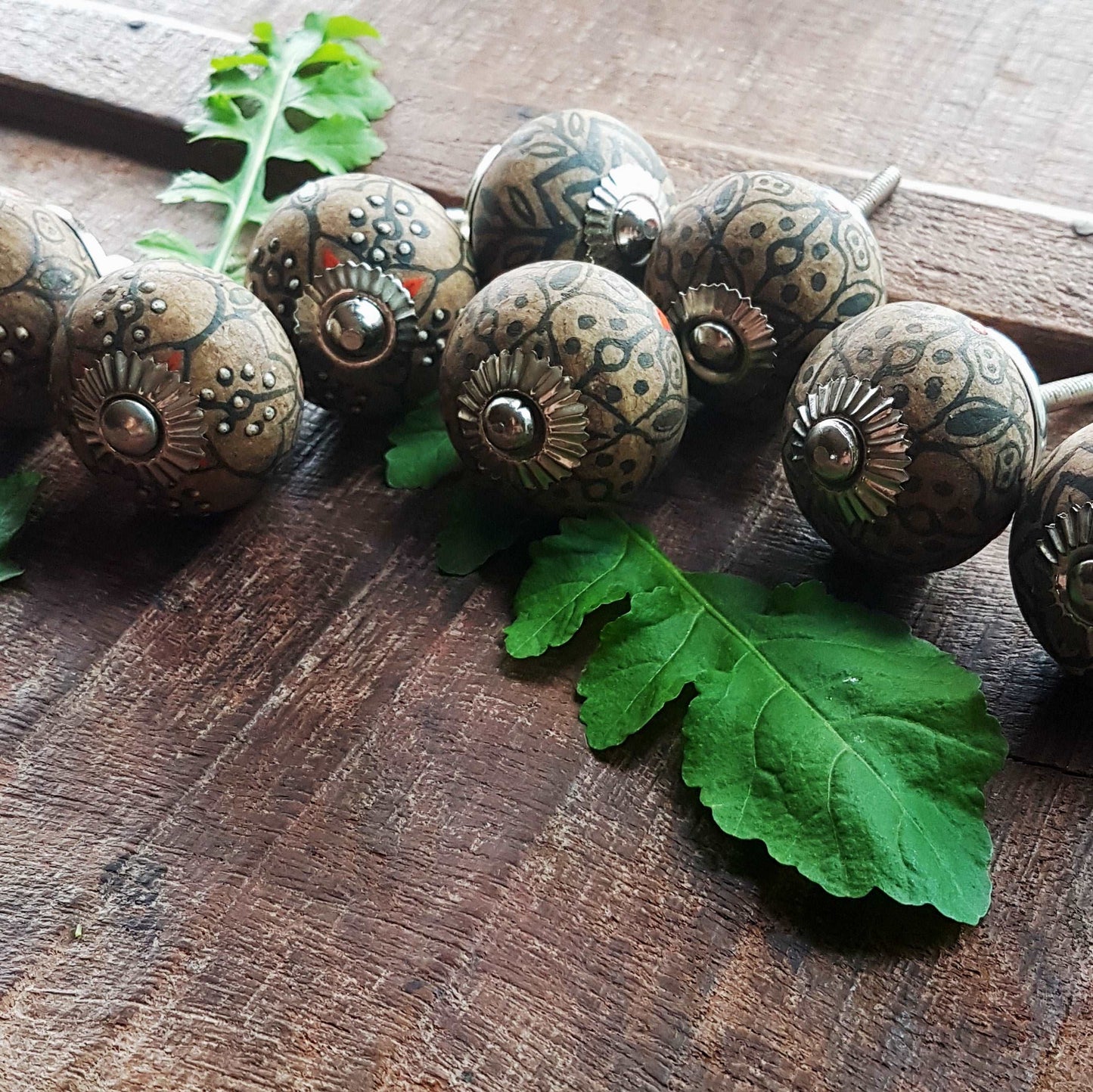 8 cabinet knobs hand painted in rustic country designs. Black & brown floral patterns with silver hardware. Easy and affordable DIY decor.