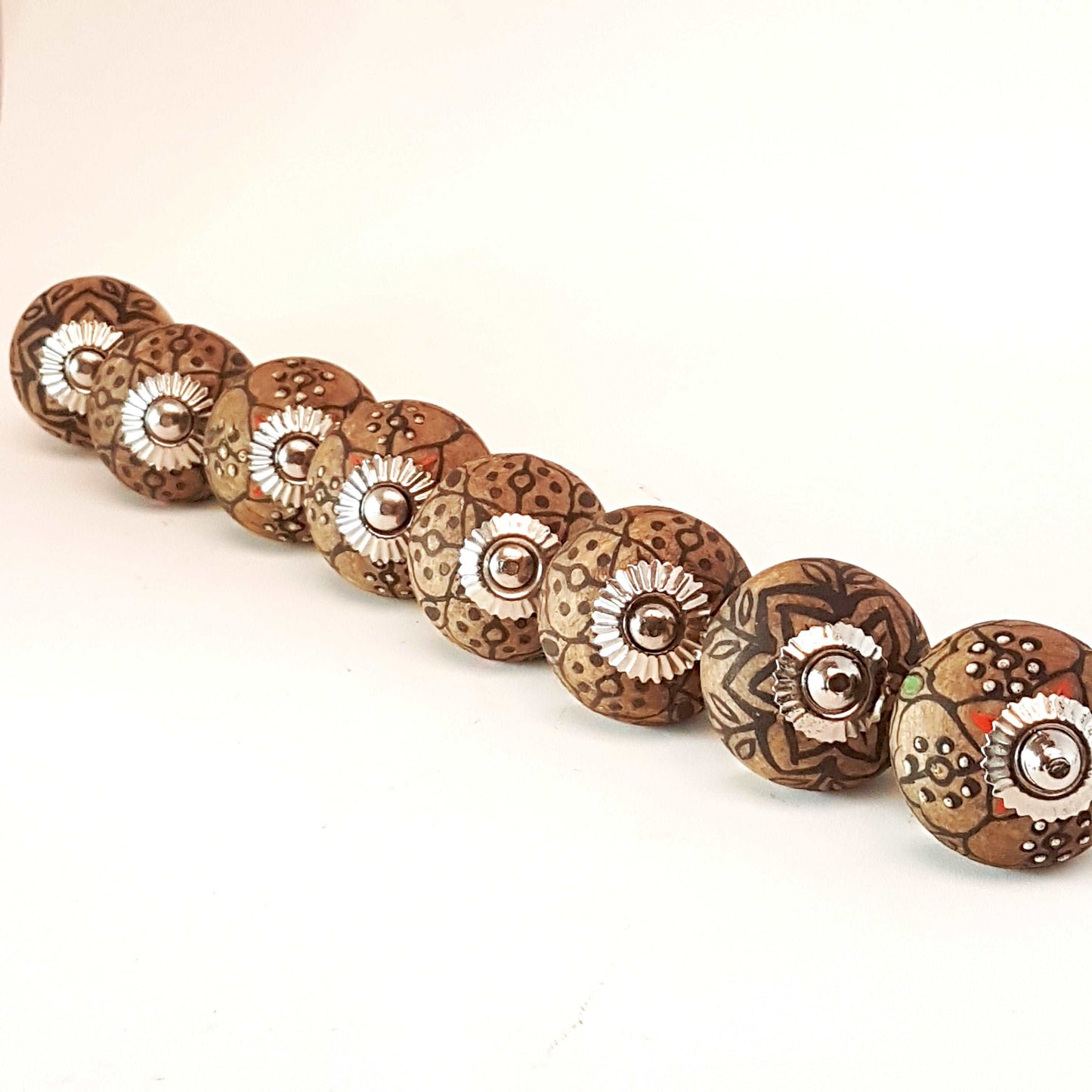 8 cabinet knobs hand painted in rustic country designs. Black & brown floral patterns with silver hardware. Easy and affordable DIY decor.