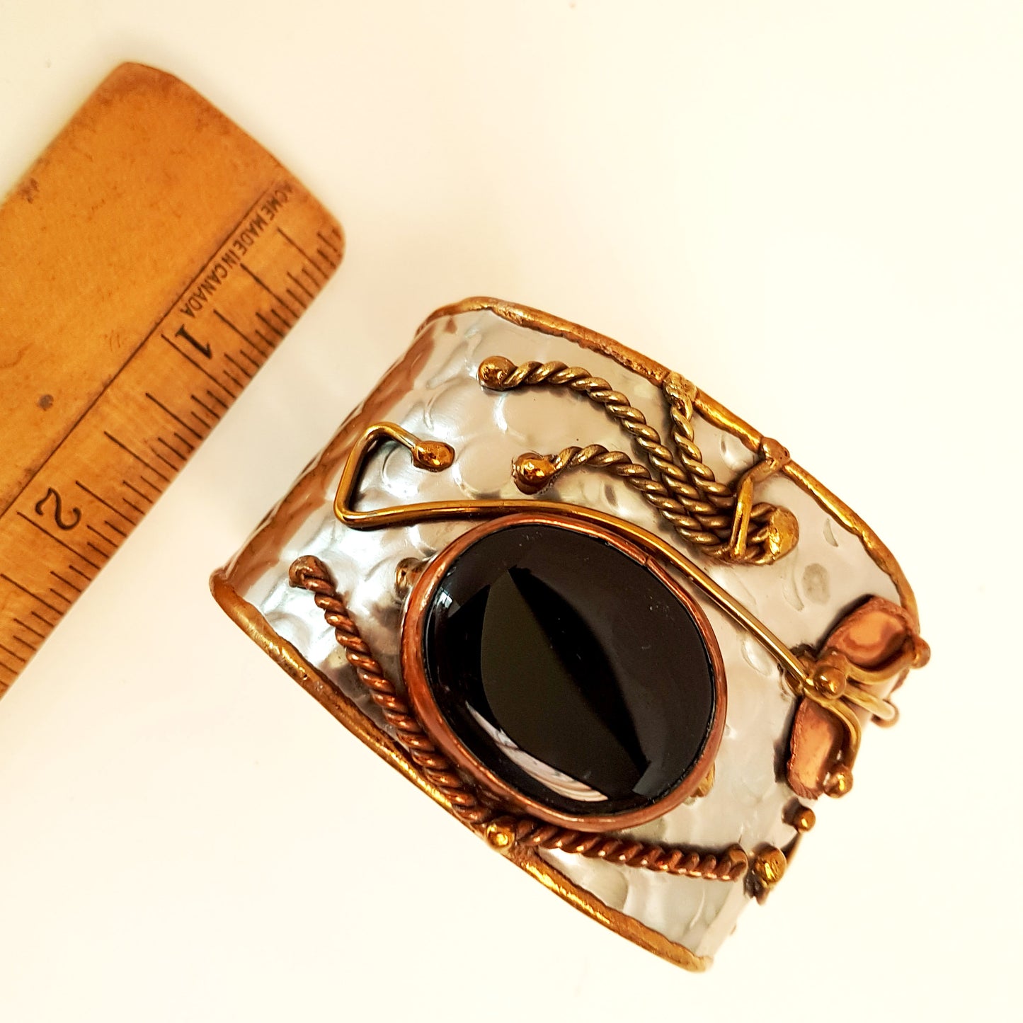 Silver cuff bracelet with a large oval shaped black onyx stone. Unique mixed metal design with copper, brass and silver. Flexible adjustable size.