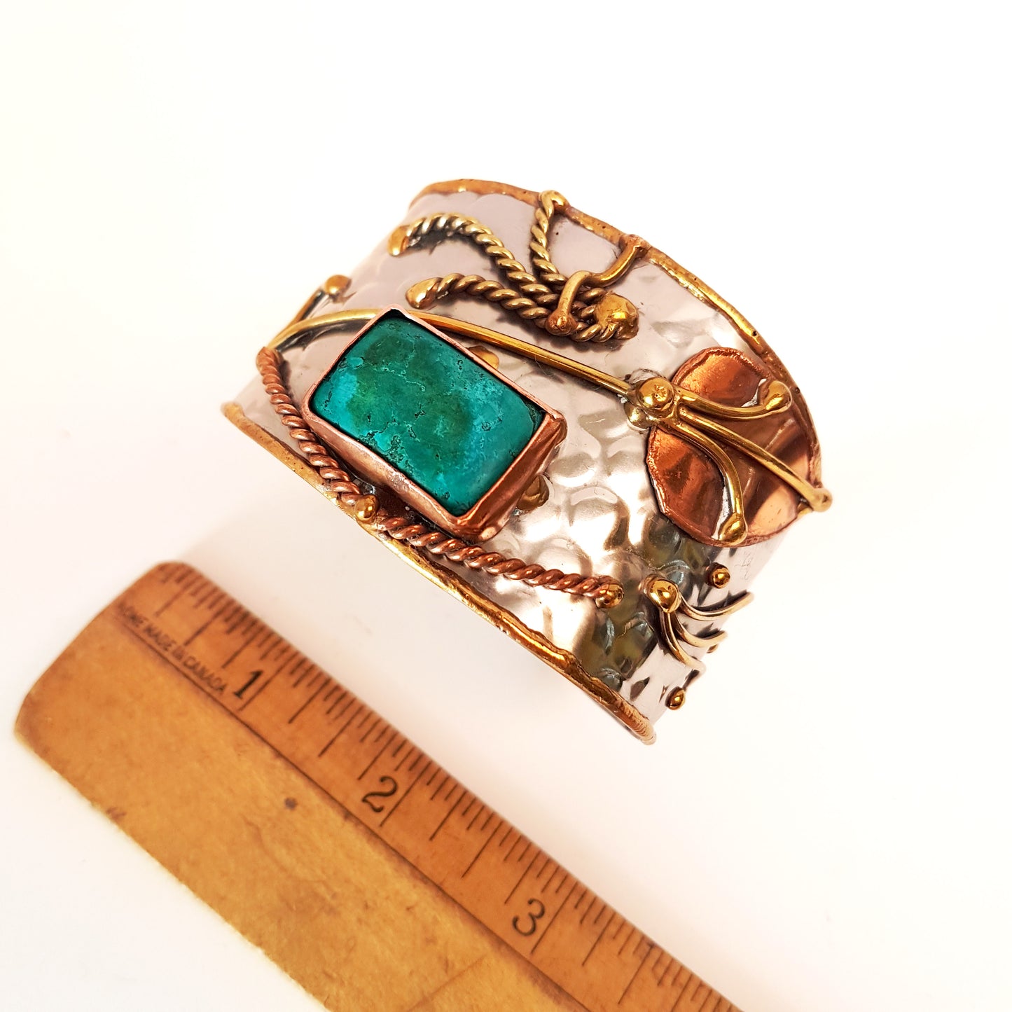 Silver cuff bracelet with an inlaid turquoise stone. Hammered trimetal design with copper & brass detail.