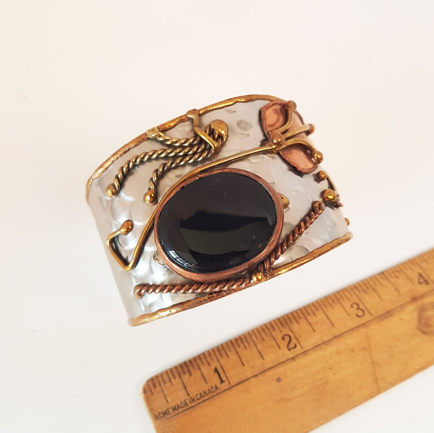 Silver cuff bracelet with a large oval shaped black onyx stone. Unique mixed metal design with copper, brass and silver. Flexible adjustable size.