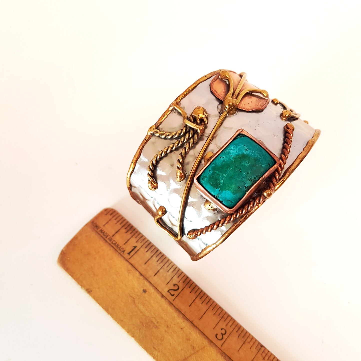 Silver cuff bracelet with an inlaid turquoise stone. Hammered trimetal design with copper & brass detail.