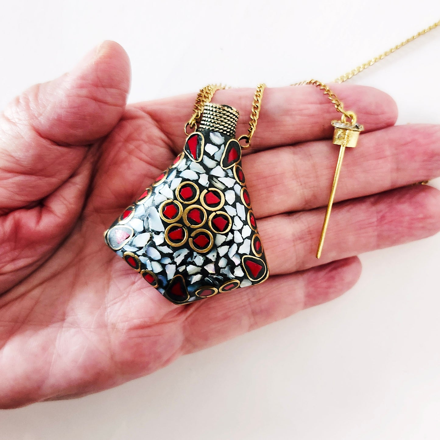 Pendentif bouteille de parfum en mosaïque de pierre. Incrusté de pierres turquoise tibétaine, lapis et MOP. La bouteille se ferme avec un bouchon en laiton.