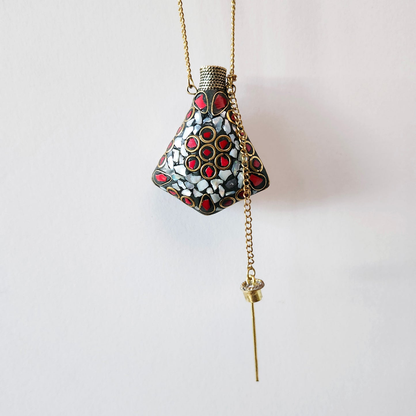 Pendentif bouteille de parfum en mosaïque de pierre. Incrusté de pierres turquoise tibétaine, lapis et MOP. La bouteille se ferme avec un bouchon en laiton.