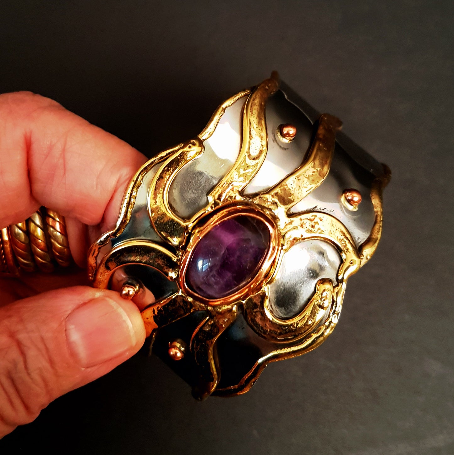 Silver cuff bracelet with inlaid gemstone center. Medieval Celtic sunrise design with brass detail. Vintage handwrought artisan metalwork.