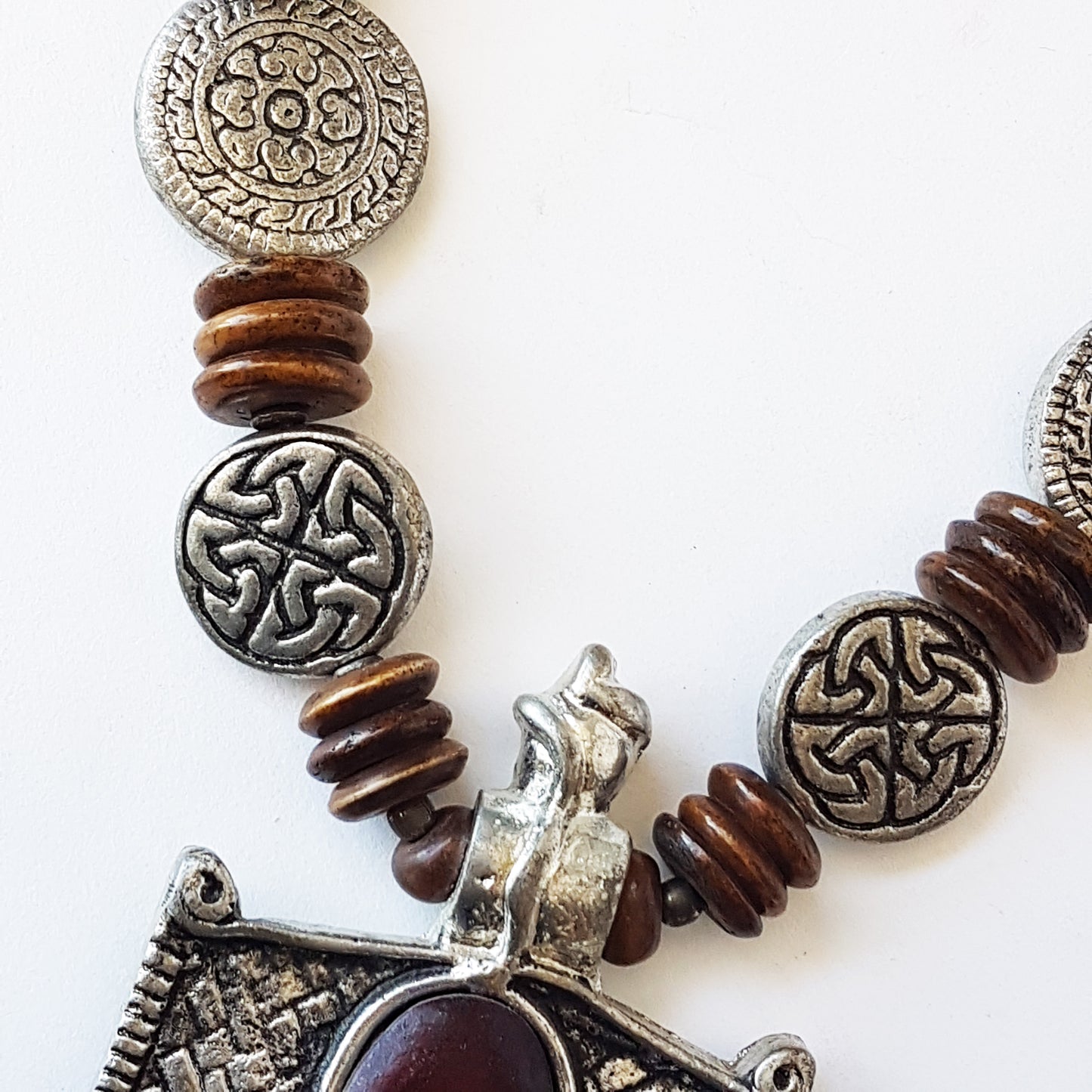 Collier pendentif hexagonal médiéval au design en étain antique. Décoré de disques de symboles d'éternité celtiques en relief et de perles marron foncé.