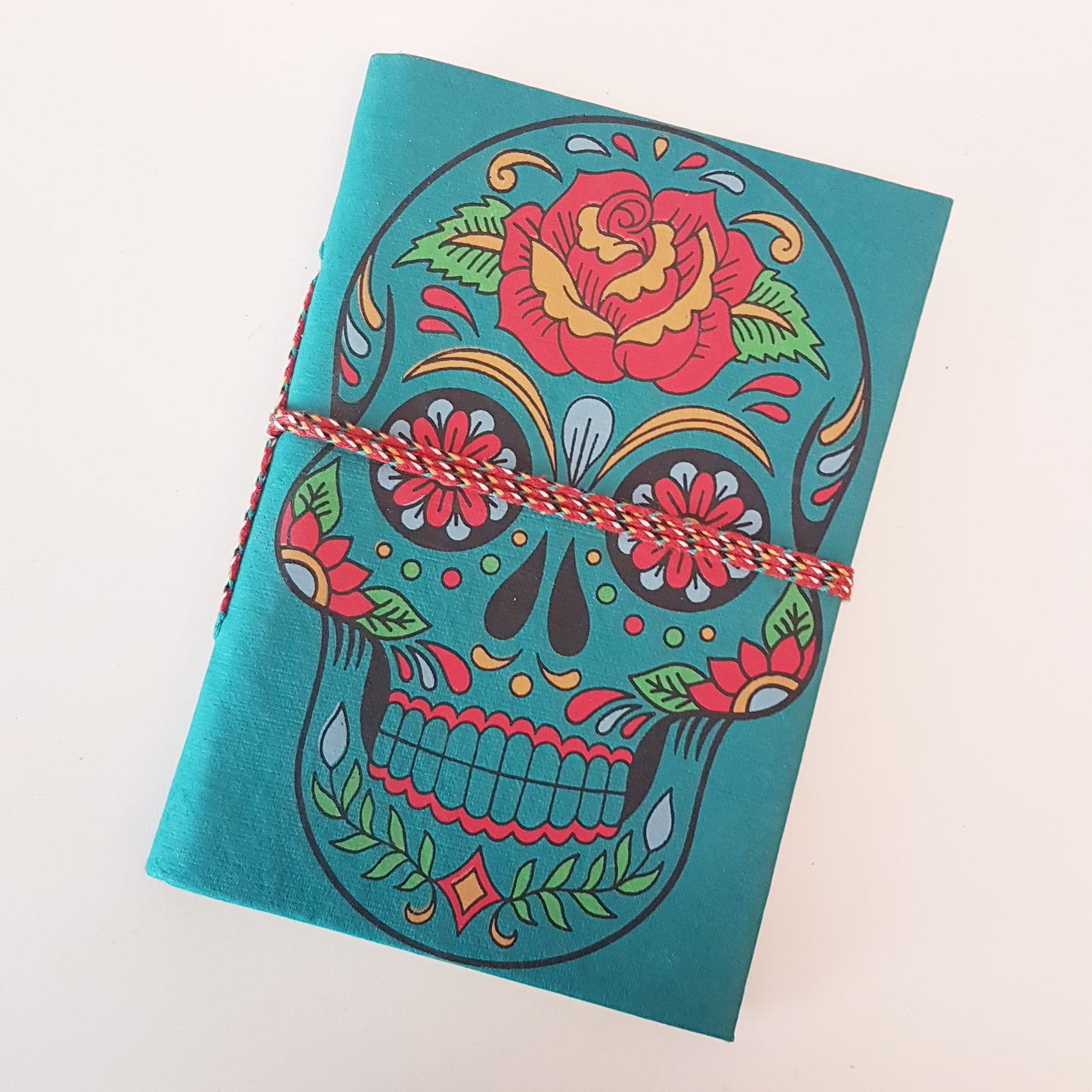 Carnet de croquis en forme de tête de mort bleu sarcelle de 12,7 x 17,8 cm avec des pages vierges en papier artisanal. Journal gothique coloré du jour des morts Sugarskull en bleu sarcelle.