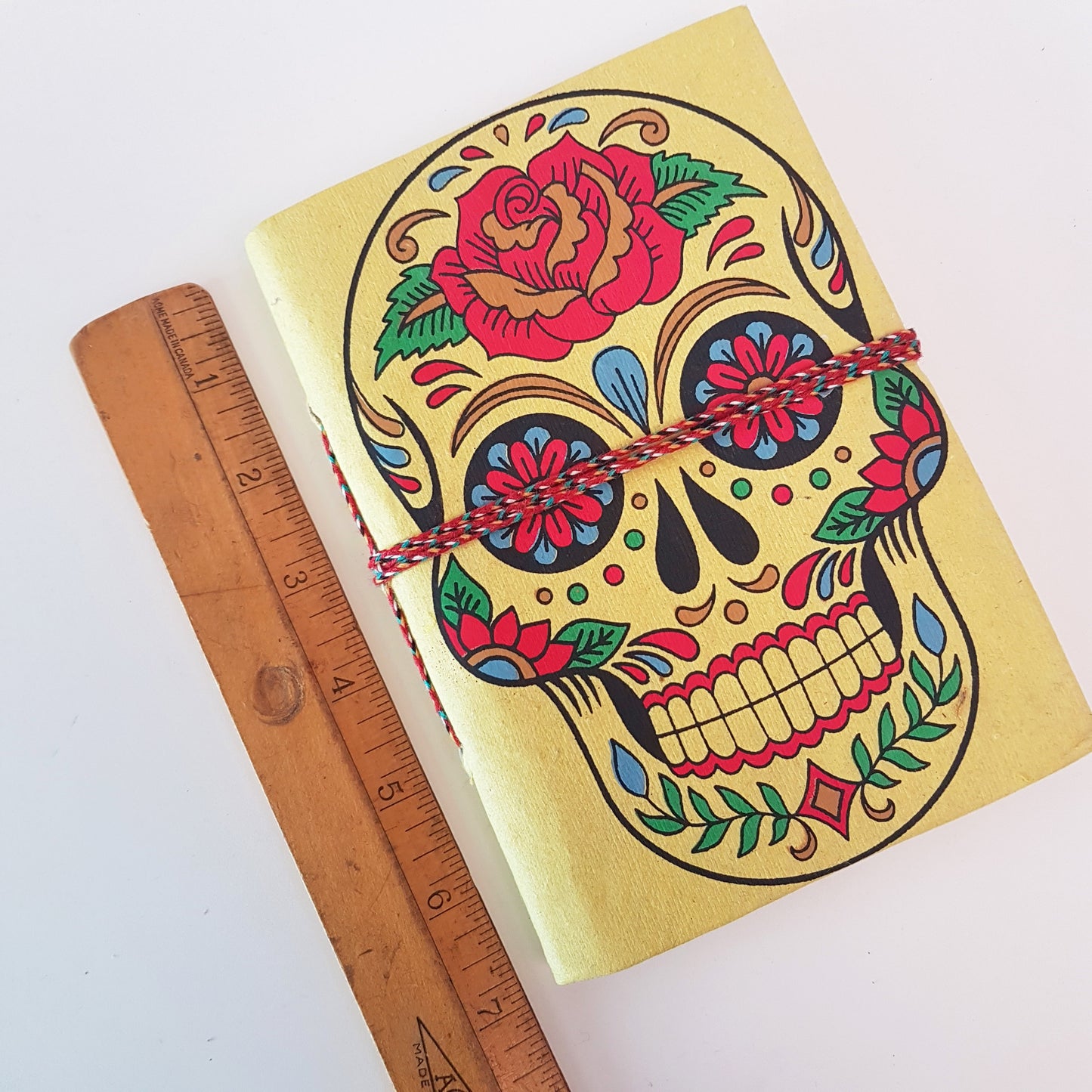 Yellow skull sketchbook jotter 5 by 7 inches with blank artisan paper pages. Colorful lemon gothic day of the dead sugarskull design diary.