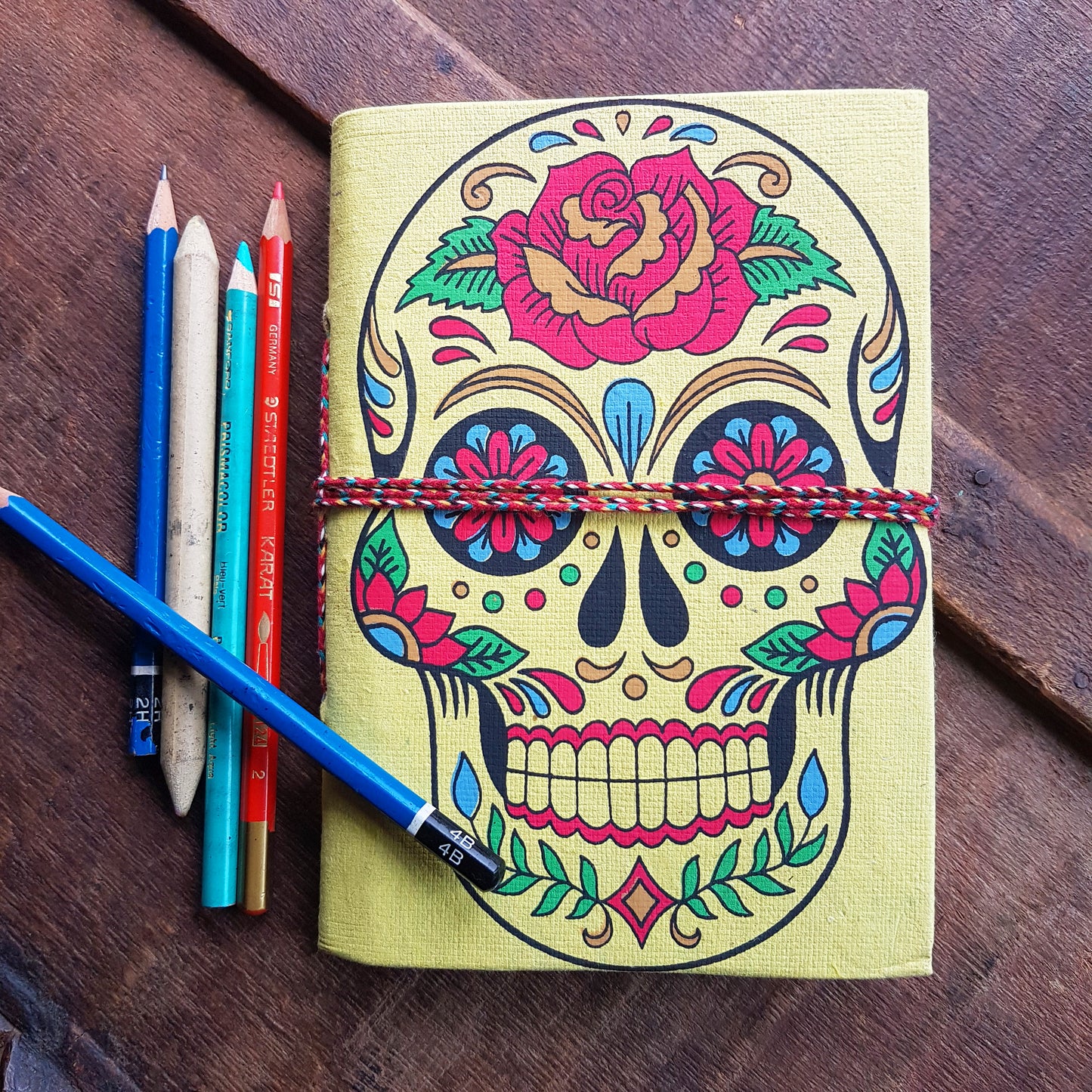 Yellow skull sketchbook jotter 5 by 7 inches with blank artisan paper pages. Colorful lemon gothic day of the dead sugarskull design diary.