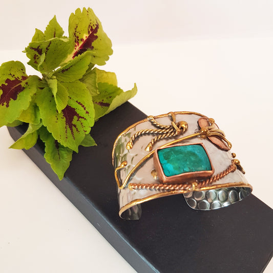 Silver cuff bracelet with an inlaid turquoise stone. Hammered trimetal design with copper & brass detail.