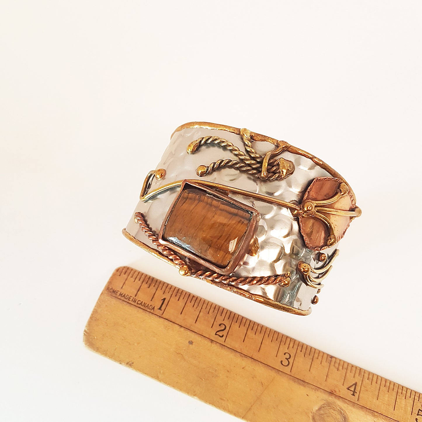 Silver cuff bracelet with rectangle shape tigereye stone. Adjustable fit. Mixed metal artisan design with copper & brass detail.